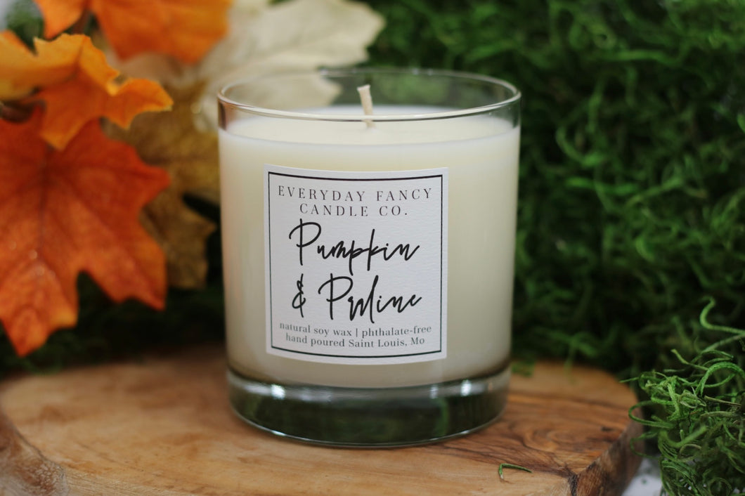 White candle in a clear glass jar with simple, classic label releasing a rich blend of pumpkin and spice. Accents of buttercream, praline, and brown sugar are complemented by sweet notes of vanilla and caramel, creating a cozy fall fragrance